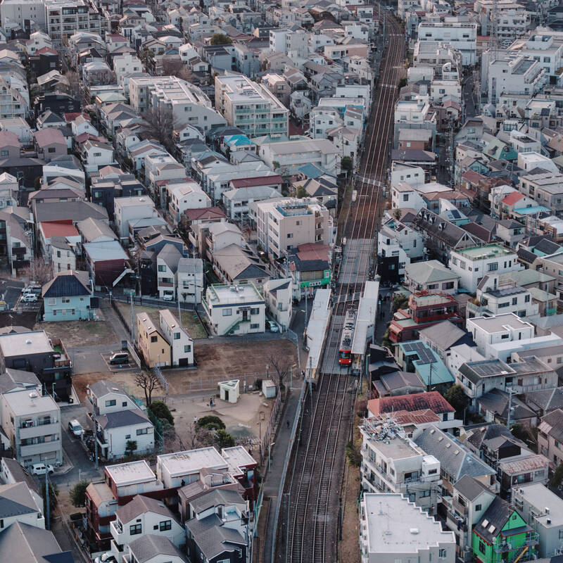 A picture of the train flanked by colorful buildings from far above.